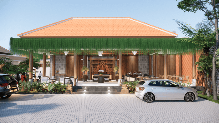 A luxurious Balinese villa entrance with traditional wood carvings, lush hanging plants, and two cars parked in the paved driveway.