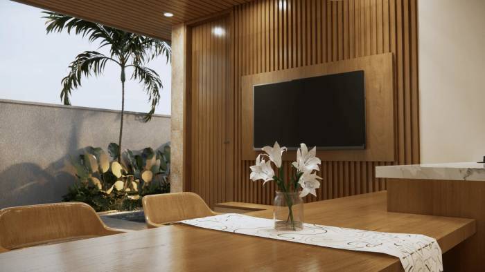 A modern dining area with a wooden table, chairs, a vase of white lilies, and a view of a lush outdoor garden and palm tree.