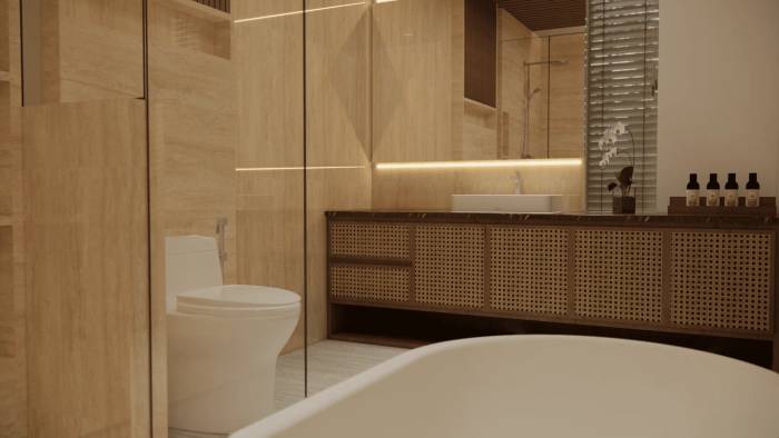 A luxurious bathroom with travertine walls, a sleek white toilet, a cane vanity, and a freestanding bathtub in a two-bedroom villa.