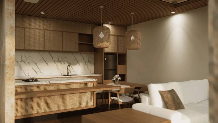 A stylish open-plan kitchen and living area featuring marble counters, rattan cabinetry, wooden accents, and a white sofa.