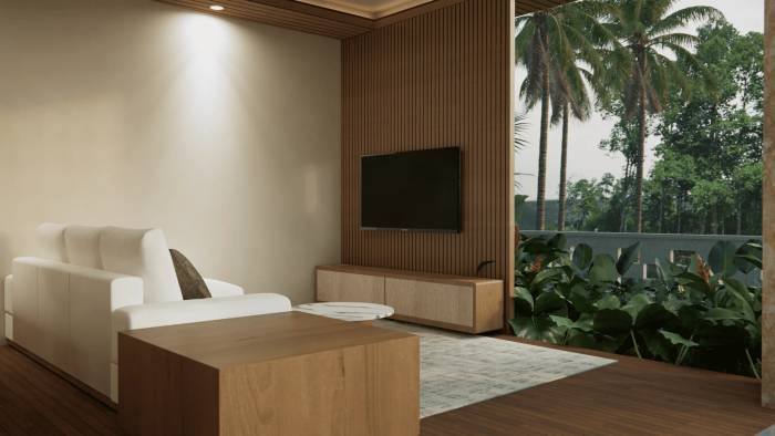 A modern living area with a white sofa, wooden coffee table, and TV on a slatted wood wall, overlooking tropical greenery.